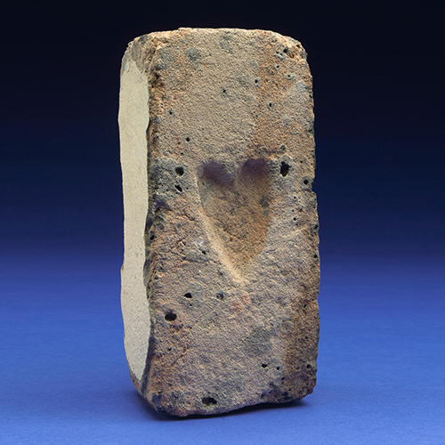 A single hand-made vintage brick of clay is stood on its end, set up under adorning studio lighting. The brick is embossed with the shape of a heart. It is a brick most likely made in Sydney, Australia, by convict labour sometime before 1840. This particular brick was offered to the market by Bonham's in New York, and sold in 2012 for US$562.50 including premium. A single hand-made vintage brick of clay is stood on its end, set up under adorning studio lighting. The brick is embossed with the shape of a heart. It is a brick most likely made in Sydney, Australia, by convict labour sometime before 1840. This particular brick was offered to the market by Bonham's in New York, and sold in 2012 for US$562.50 including premium.